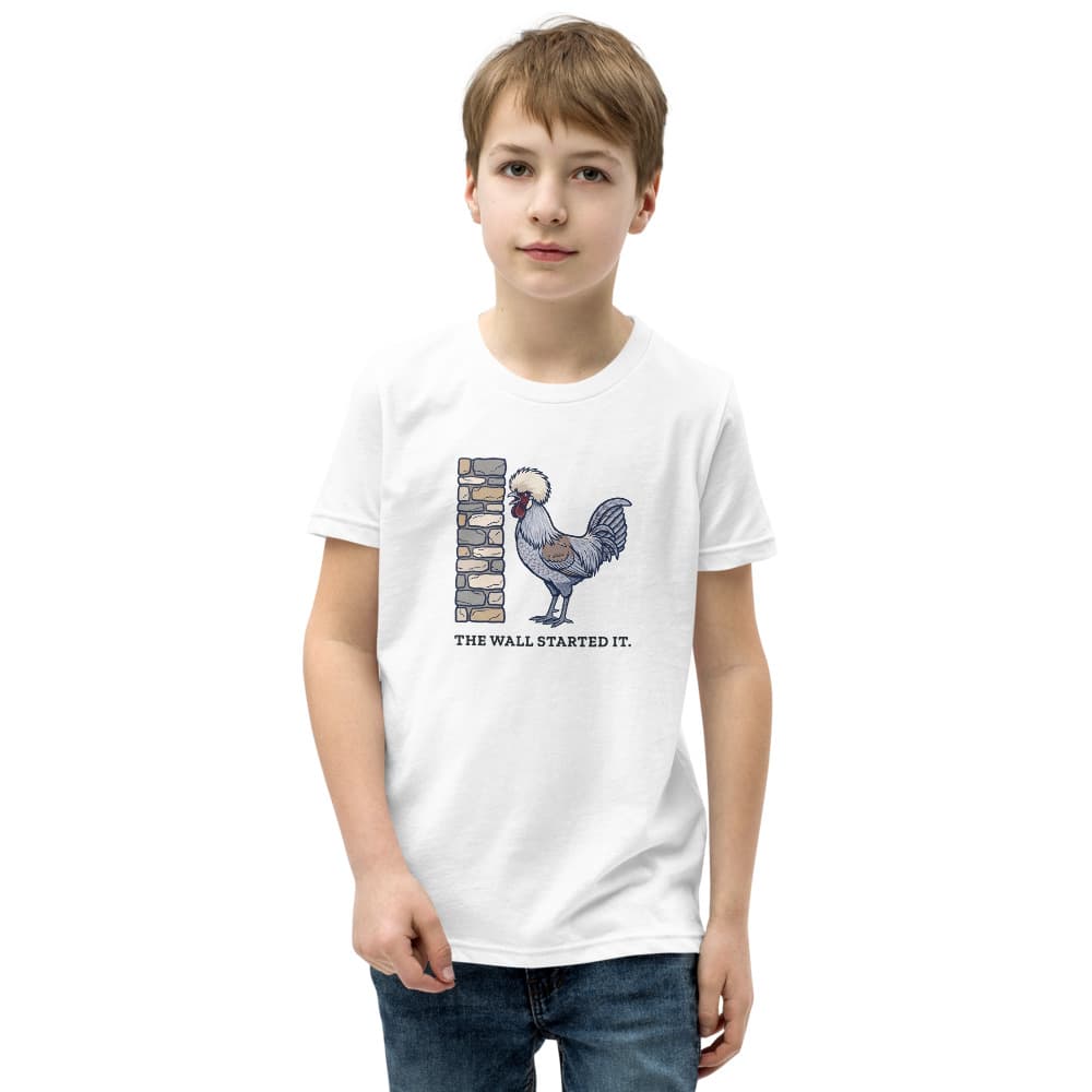 Kids t-shirt with a cartoon of a small crested rooster crowing at a stone wall and the words The Wall Started It. Shown in White.
